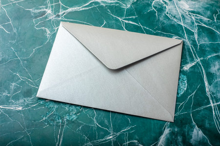 Silver envelope on turquoise background. Mock-up