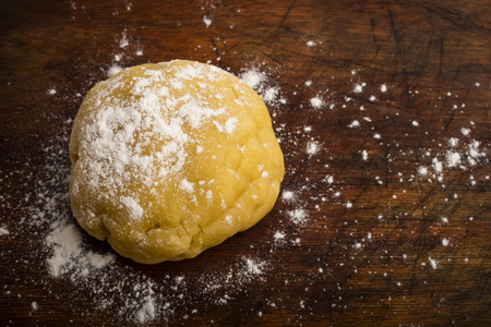 ball of dough sprinkled with flour on a wooden cutting board, copy spaceの写真素材