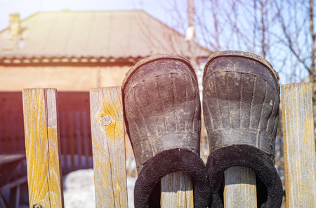 Old shoes on a wooden fence. Spring season with sun raysの写真素材