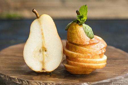 Fresh pears on a wooden board, cut into pieces, decorate with mint leaves. Copy space for your text. dark backgroundの写真素材