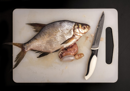 Cutting up fresh bream fish on a plastic board for dressing. Top viewの写真素材