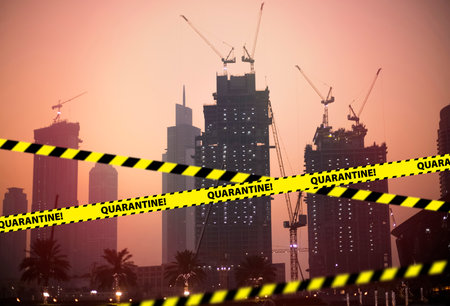 Barrier tape - quarantine, isolation, entry ban. Do not cross. Construction crane and building house at sunsetの写真素材