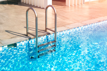 metal staircase leads to the pool. Blue water in the pool of a large house, hotel. Copy space for textの写真素材