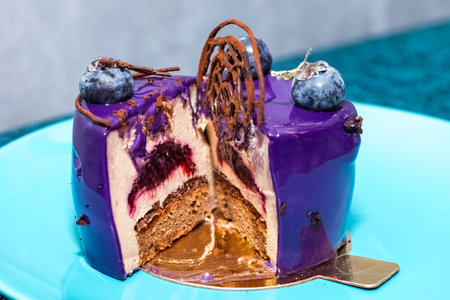 delicious cake with fresh blueberries and chocolate decor. Cutaway cake on a blue plateの写真素材