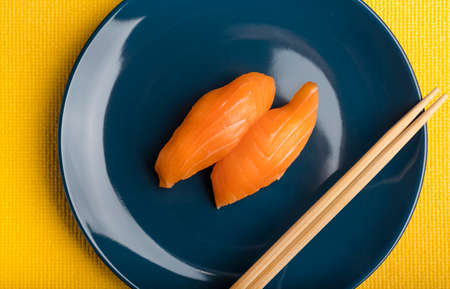 Sushi with salmon and sticks on a blue plate. Top viewの写真素材