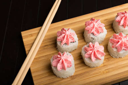 rolls with pink lava sauce on a bamboo board. Serving Japanese food on a wooden table. Close-upの写真素材