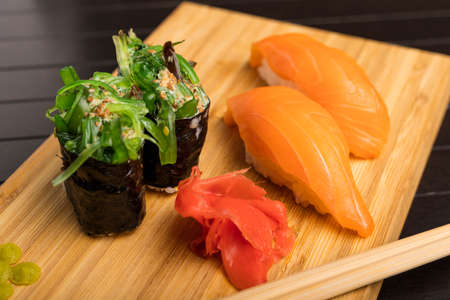 Chukka gunkan seaweed rolls and salmon sushi on a bamboo packing board. Serving Japanese food. Close-upの写真素材