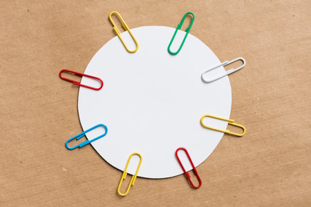 white circle with colored paper clips. Brown background from kraft paper. Blank template for text, copy spaceの写真素材