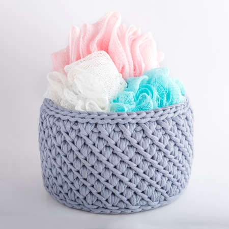 gray handmade basket with colored washcloths. texture of knitted fabric braids. Decorative element in the interiorの写真素材