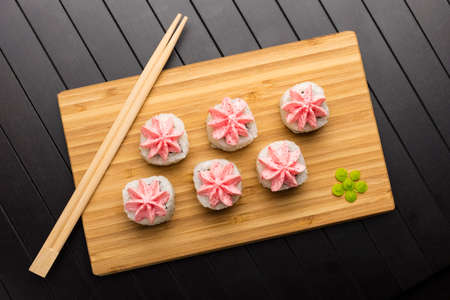 rolls with pink lava sauce on a bamboo board. Serving Japanese food on a wooden table. Top viewの写真素材