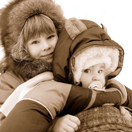Photo of two lovely children in cloudy weather with an easy snow ( isolated on white / Sepia effects )の写真素材