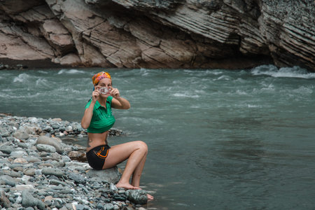 tourist girl sitting in a mountain riverの写真素材