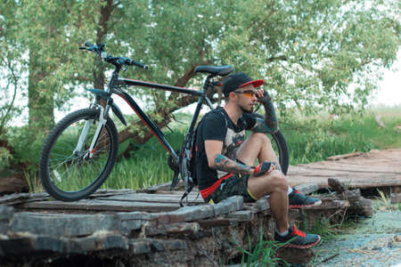 the guy with the bike sitting on the bridge admiring the natureの写真素材