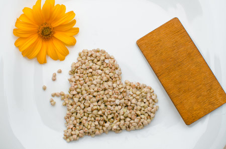 photo of germinated buckwheat on a white plate next to a green leaf and a yellow flower