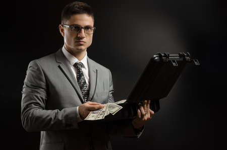 a man in a suit jacket with a case of moneyの写真素材