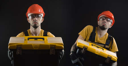 a young man posing on a black background in a work uniform and a construction toolの写真素材