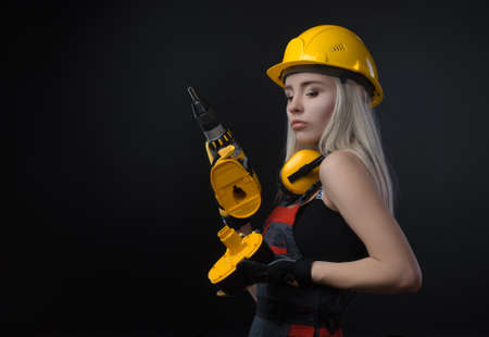 girl in construction clothes and protective equipment posing with a screwdriverの写真素材