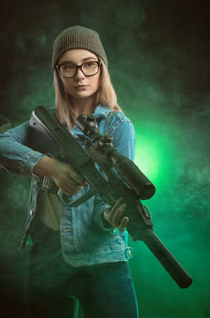 girl with a gun posing on a black background sniper scopeの写真素材
