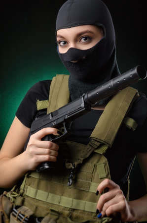 the girl in military special clothes posing with a gun in his hands on a dark background in the hazeの写真素材