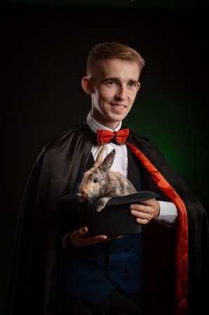 a young guy magician illusionist holding a hat with a rabbitの写真素材