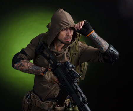 man Stalker with a gun with an optical sight and a backpack on a dark background