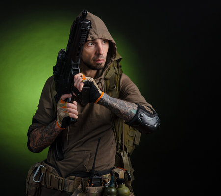 man Stalker with a gun with an optical sight and a backpack on a dark background