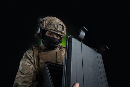 a male soldier in military clothes with a weapon on a dark background