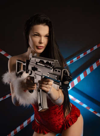 girl in red Christmas bodysuit and Santa Claus hat with a firearm in handの写真素材