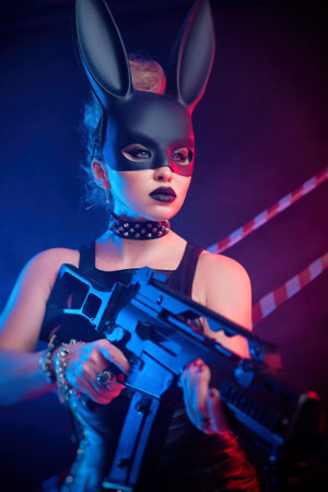 a woman in a leather dress and a black rabbit mask with a gun in her handsの写真素材