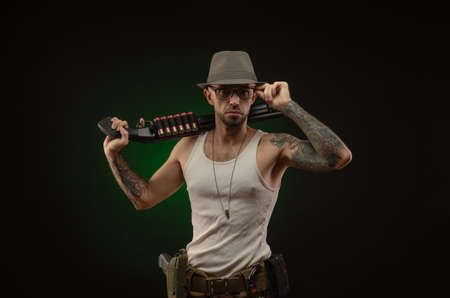 an athletic guy with a tattoo poses with a shotgunの写真素材