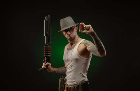 an athletic guy with a tattoo poses with a shotgunの写真素材