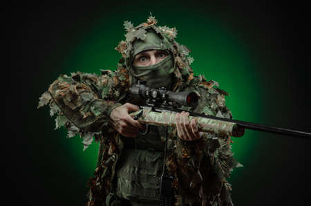sniper in a poncho camouflage suit and a sniper rifleの写真素材