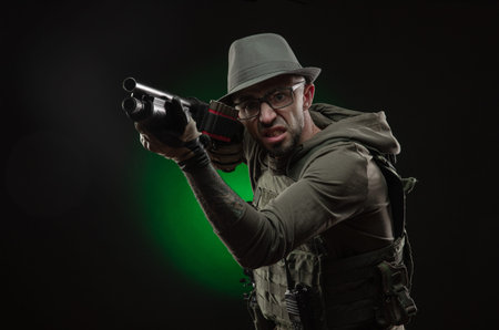 an athletic guy with a tattoo poses with a shotgun