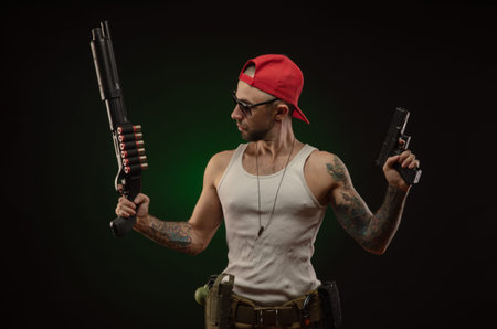 an athletic guy with a tattoo poses with a shotgun