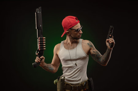 an athletic guy with a tattoo poses with a shotgun