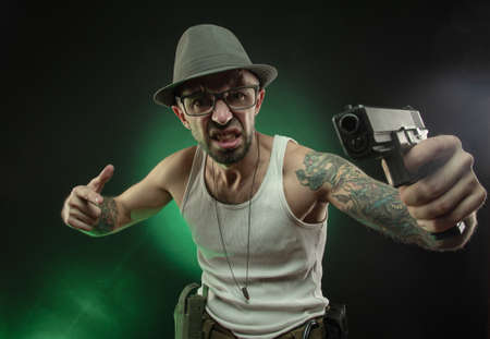an athletic guy with a tattoo poses with a pistolの写真素材