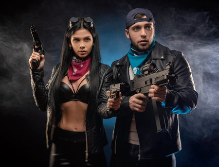 a girl and a guy in a leather jacket with a gun