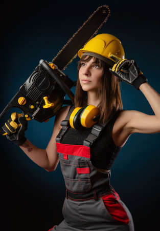 Girl in overalls with a chainsawの写真素材
