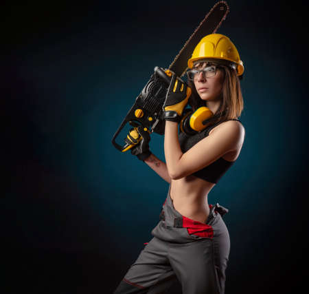Girl in overalls with a chainsawの写真素材