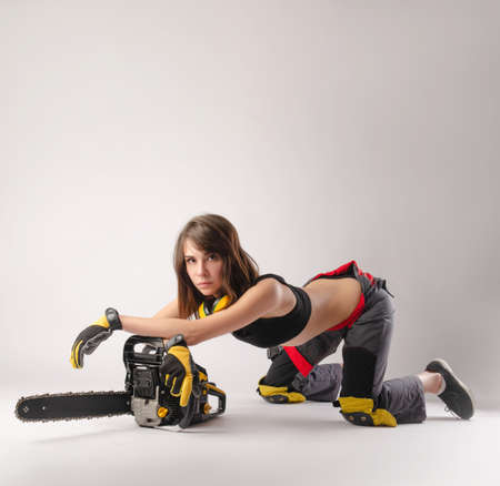 the Girl in overalls with a chainsawの写真素材