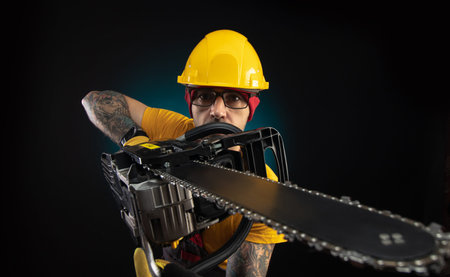 a guy in protective overalls with a chainsaw on a dark background