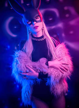 sexy girl in a bodysuit and fur coat with a rabbit mask in the neon lightの写真素材