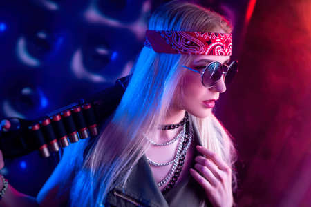 A girl who looks like a hippie with a shotgun in neonの写真素材