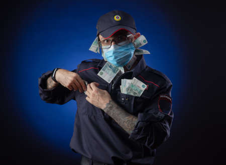 a guy in a police uniform Russian police officer in a medical mask with money in his hands. English translation of " Police"の写真素材