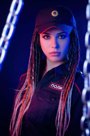 a girl in a police uniform with dreadlocks in neon light with chains and handcuffs English translation the policeの写真素材