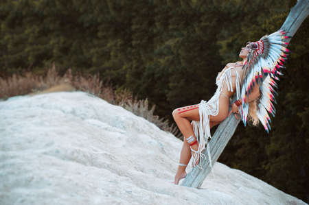 a woman in the image of the indigenous peoples of America posing in natureの写真素材