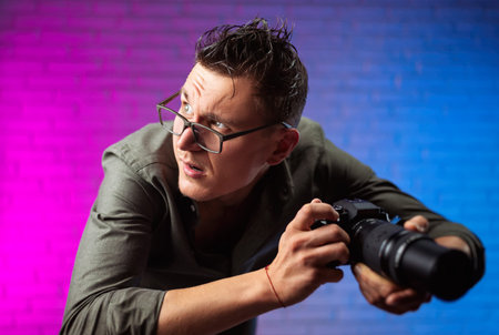 crazy man in glasses with a digital camera on a bright neon background