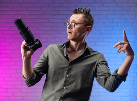 crazy man in glasses with a digital camera on a bright neon background