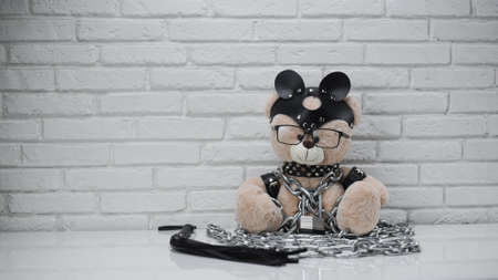 toy bear dressed in leather straps harness accessory for BDSM chained with a lockの写真素材
