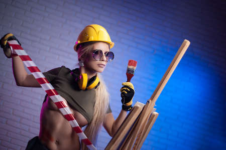 sexy woman in construction helmet in with a brush draws on an easel creativeの写真素材